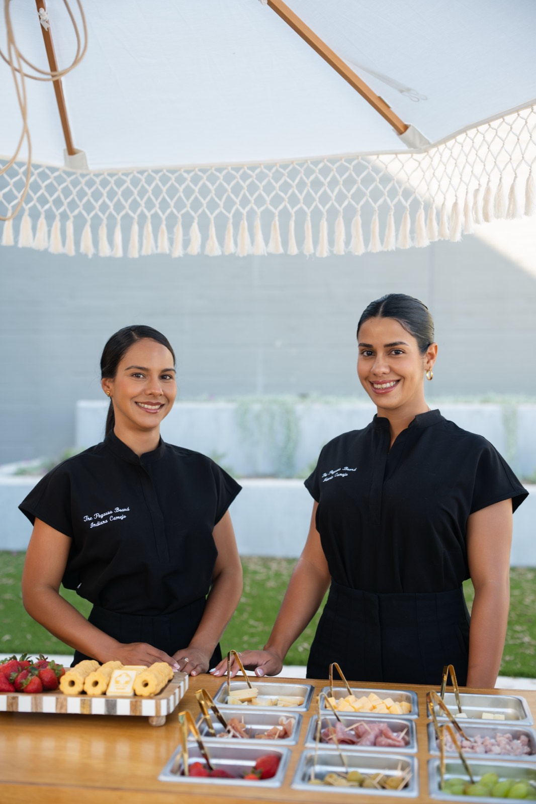 Dos anfitrionas uniformadas detrás del buffet de charcutería